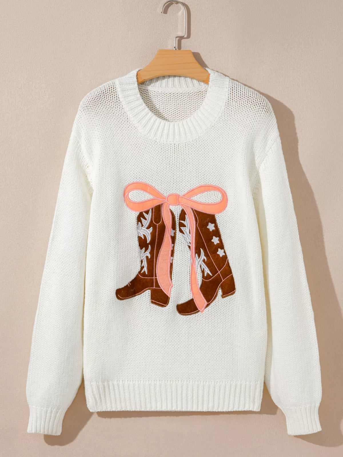 Women's Embroidered Bow Boots Drop Shoulder Sweater in cream, laid flat showing the detailed boot and bow design on the front.