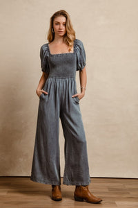 BiBi Smocked Denim Jumpsuit with square neck and puff sleeves on model