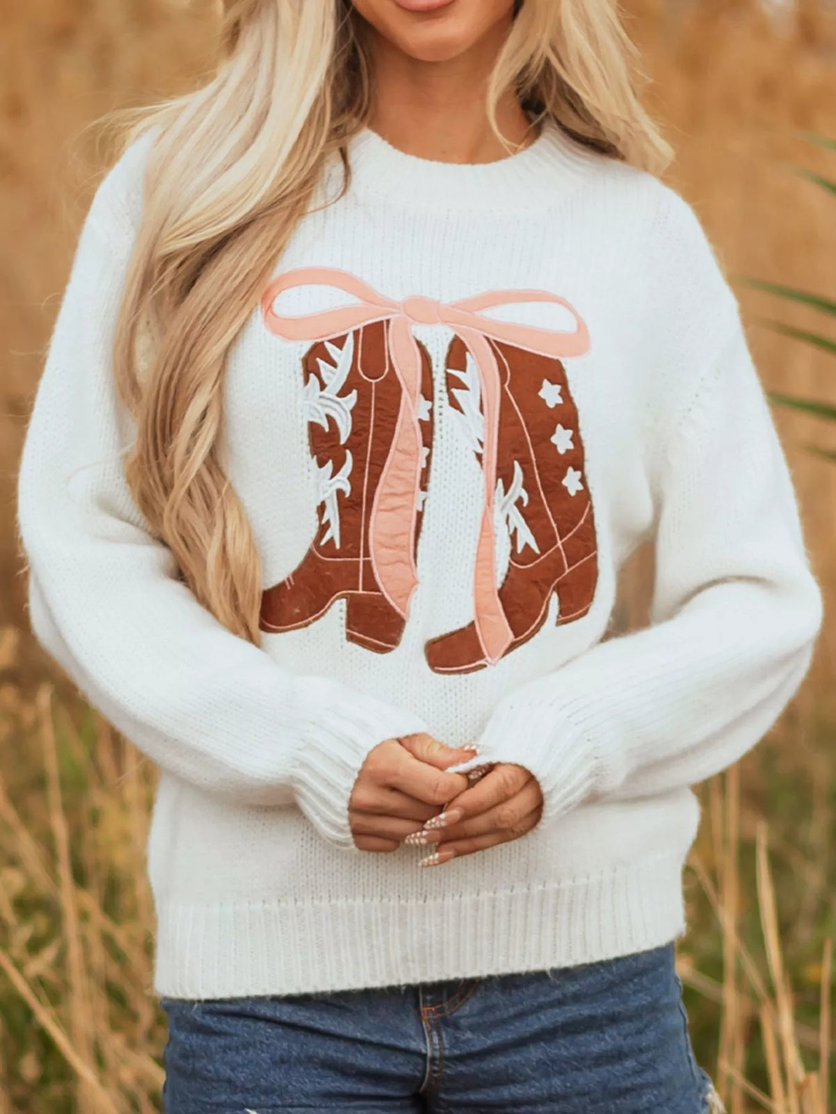 Women's Embroidered Bow Boots Drop Shoulder Sweater in cream, laid flat showing the detailed boot and bow design on the front.