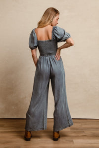 BiBi Smocked Denim Jumpsuit with square neck and puff sleeves on model