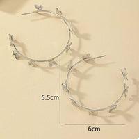 Butterfly Vine Hoop Earrings in 18K gold-plated metal, shown on a woman's ear.