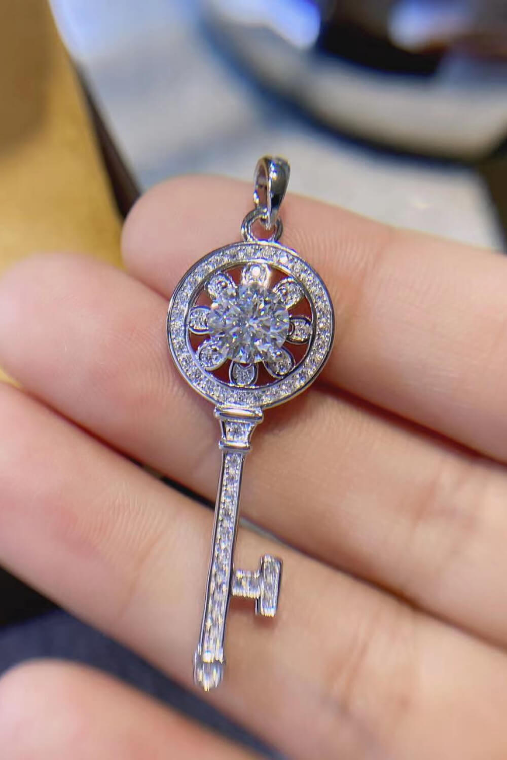 Moissanite key pendant necklace in platinum plating held in hand with sparkling detail.
