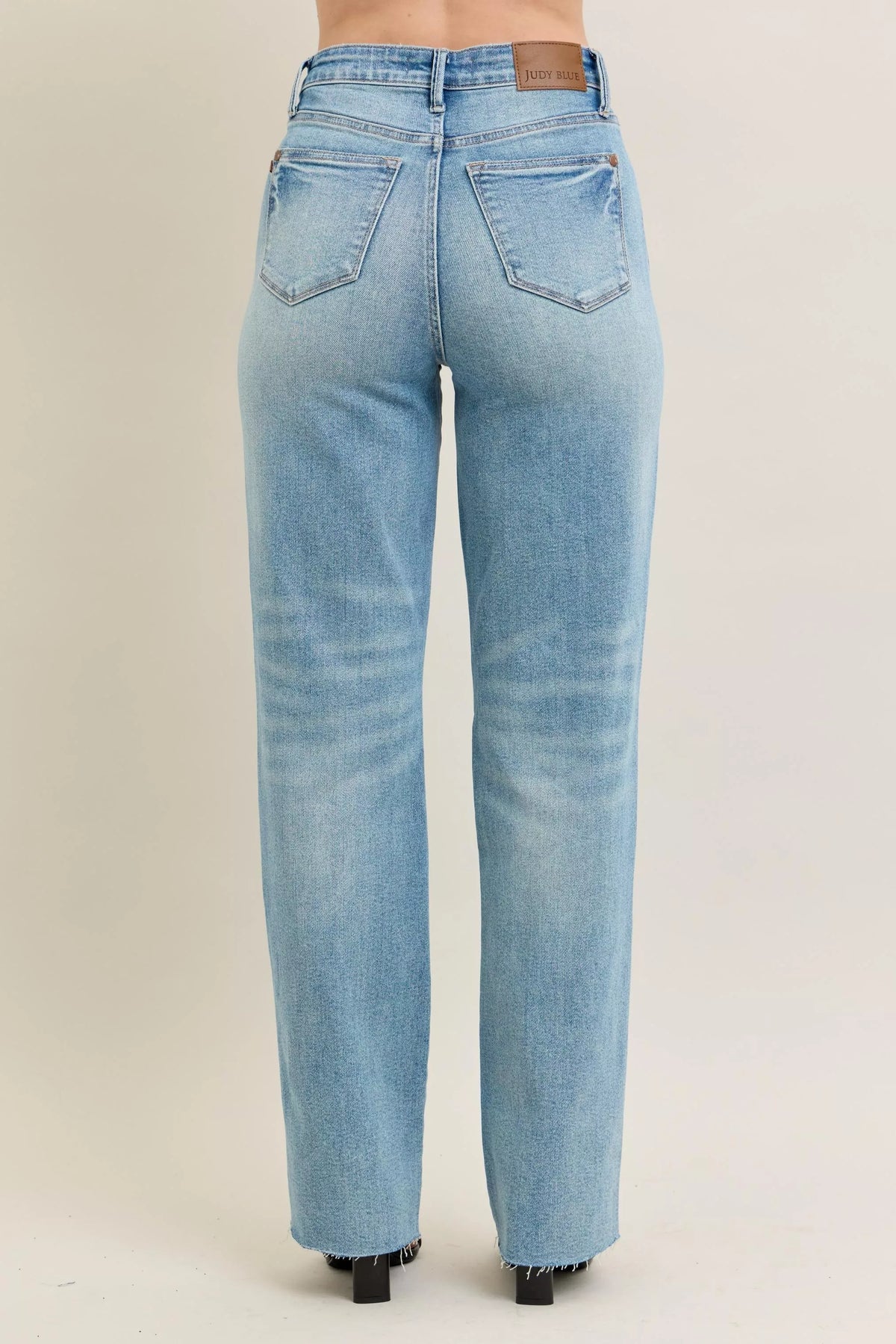 Judy Blue 90s Straight Jeans in a distressed wash, modeled from the front, showing the high waist and straight leg fit.