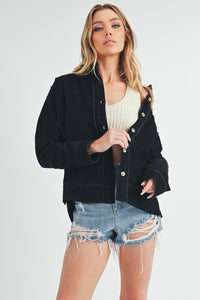 A stylish corduroy jacket featuring a button-up front, side slits, and exposed seam detailing. The jacket has a tailored fit with a collar and long sleeves, perfect for a modern, casual look. The textured corduroy fabric adds a touch of vintage-inspired charm.